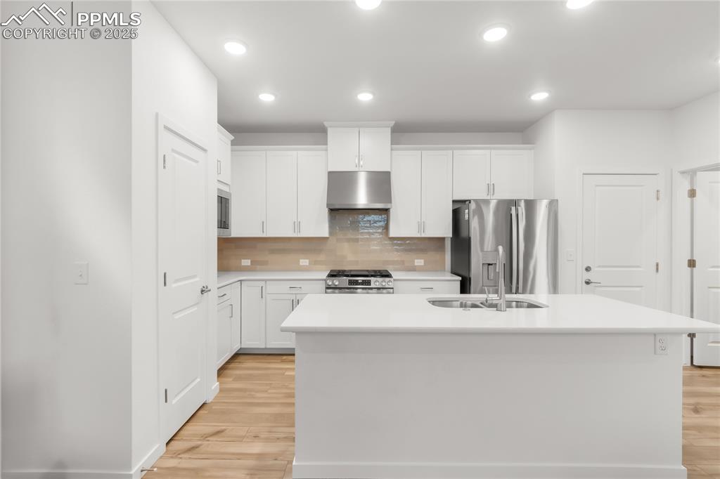 Image 33 of 39: Kitchen with under cabinet range hood, tasteful backsplash, stainless steel