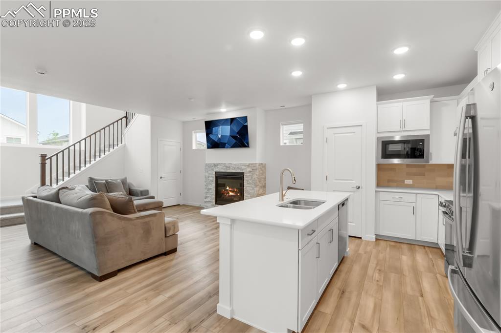 Image 35 of 39: Kitchen featuring open floor plan, light countertops, a stone fireplace, li
