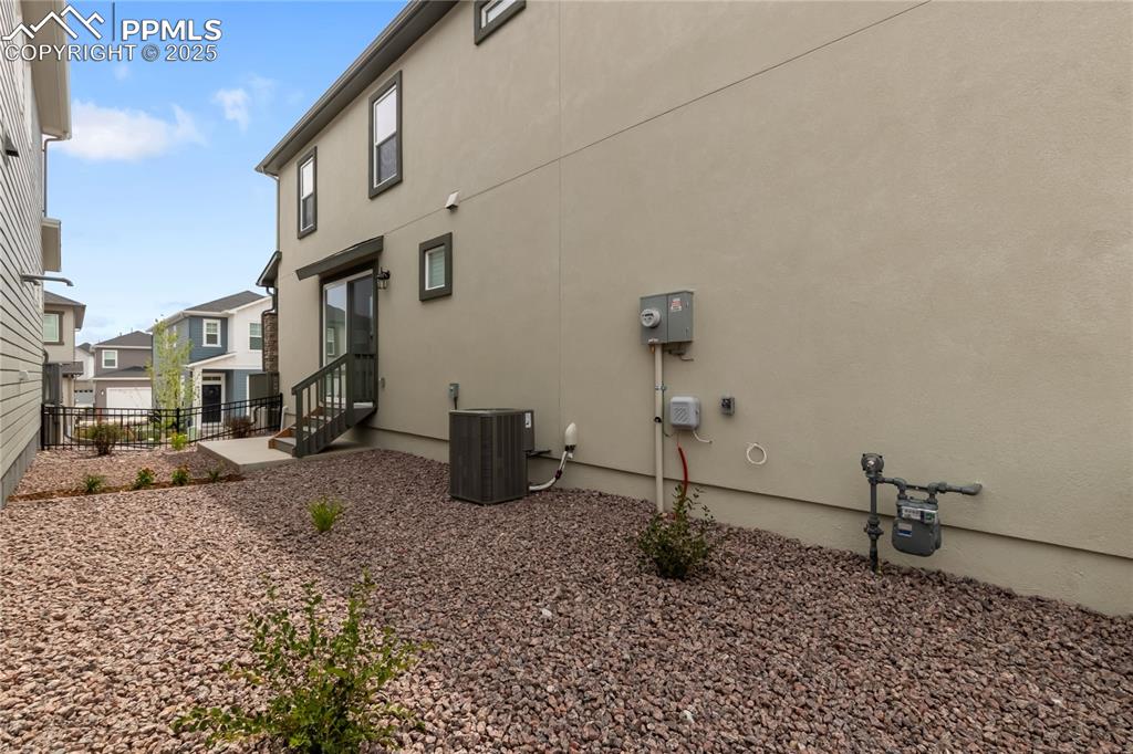 Image 36 of 39: View of side of home with stucco siding and entry steps