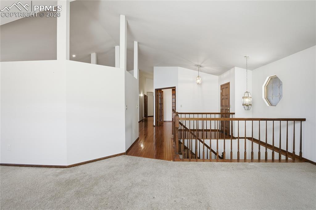 Image 18 of 47: Hall featuring dark colored carpet, an upstairs landing, and high vaulted c