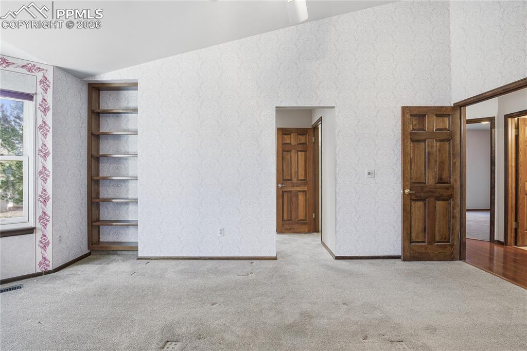 Image 22 of 47: Unfurnished bedroom with wallpapered walls, vaulted ceiling, and carpet flo