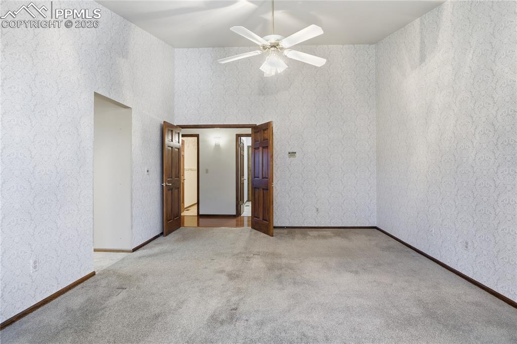 Image 23 of 47: Unfurnished bedroom with wallpapered walls, light carpet, and ceiling fan