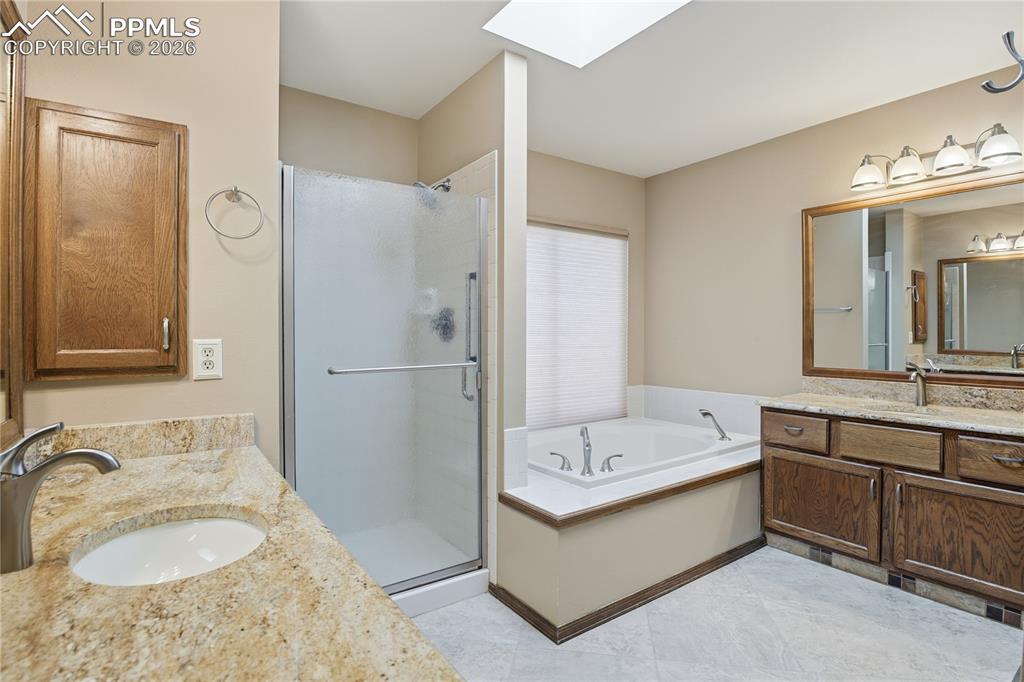 Image 24 of 47: Bathroom with a skylight, two vanities, a bath, and a shower stall