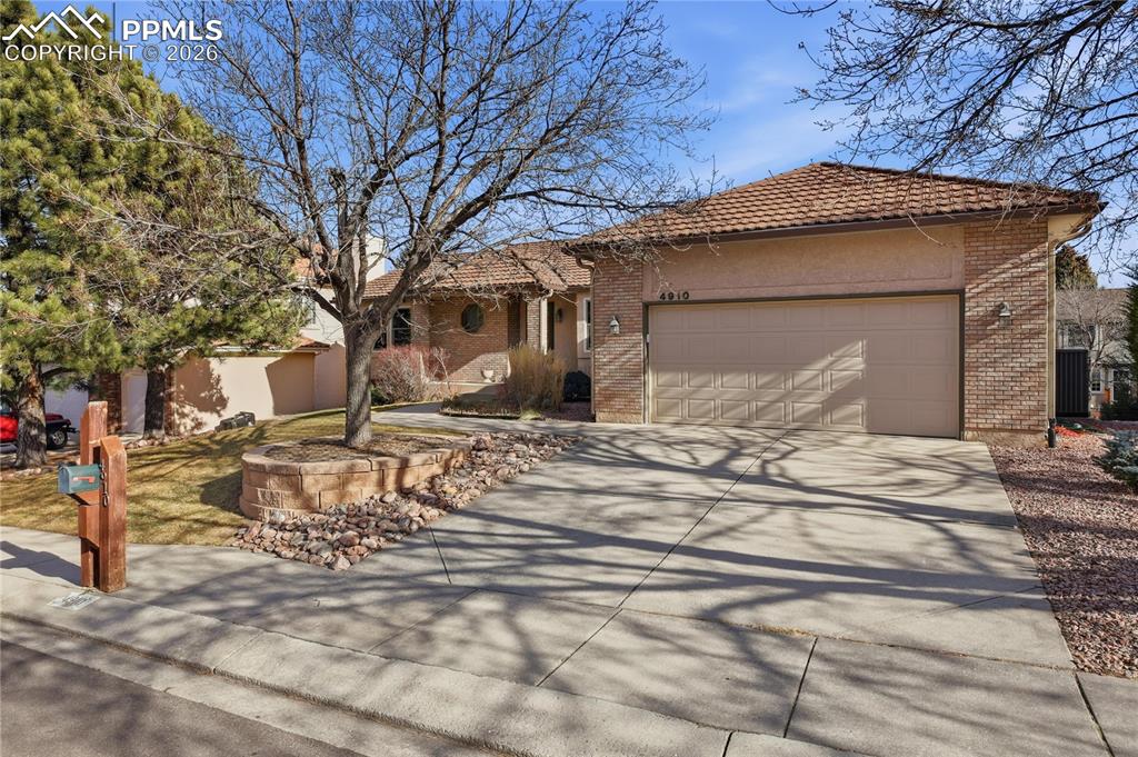 Image 3 of 47: Ranch-style home featuring driveway, a garage, a tile roof, and brick sidin