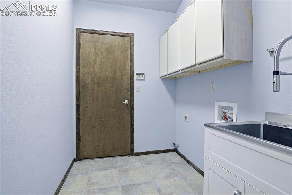 Image 30 of 47: Laundry area featuring hookup for an electric dryer, cabinet space, and was
