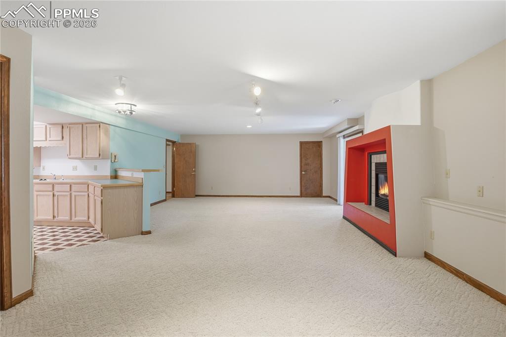 Image 36 of 47: Kitchen with a fireplace, light brown cabinets, light colored carpet, and o