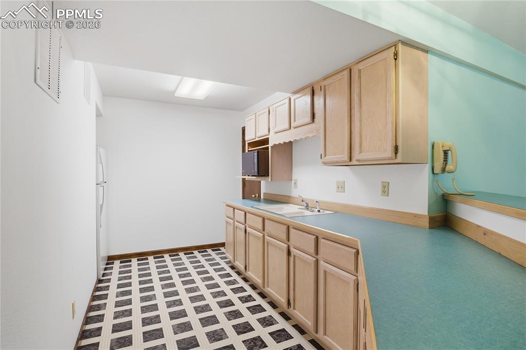 Image 37 of 47: Kitchen with light brown cabinets, light countertops, freestanding refriger