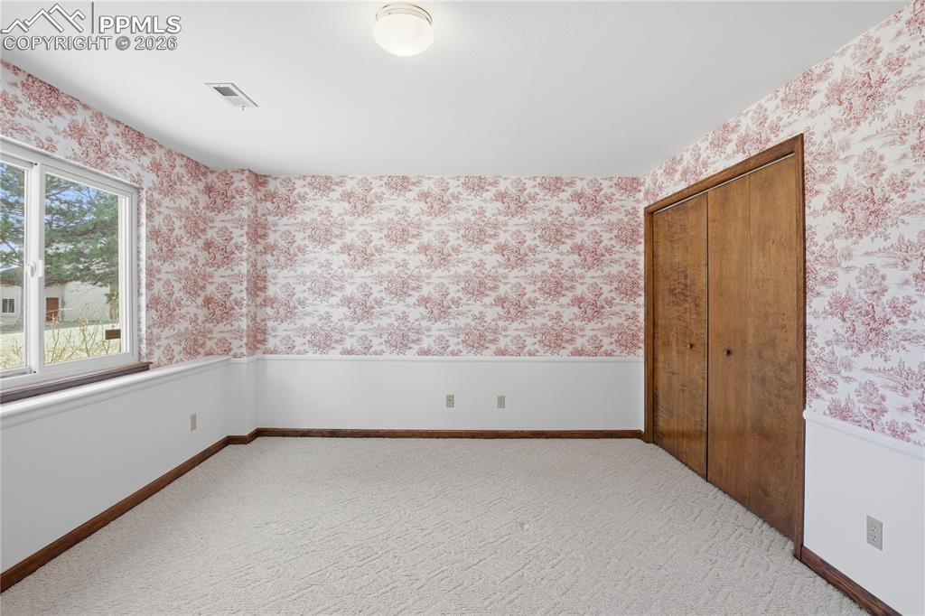 Image 39 of 47: Unfurnished bedroom featuring wallpapered walls, a wainscoted wall, carpet 