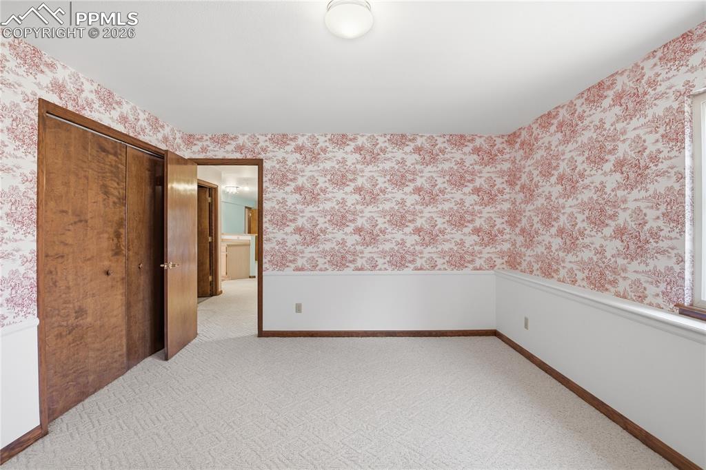 Image 40 of 47: Unfurnished room with wallpapered walls, light carpet, and wainscoting