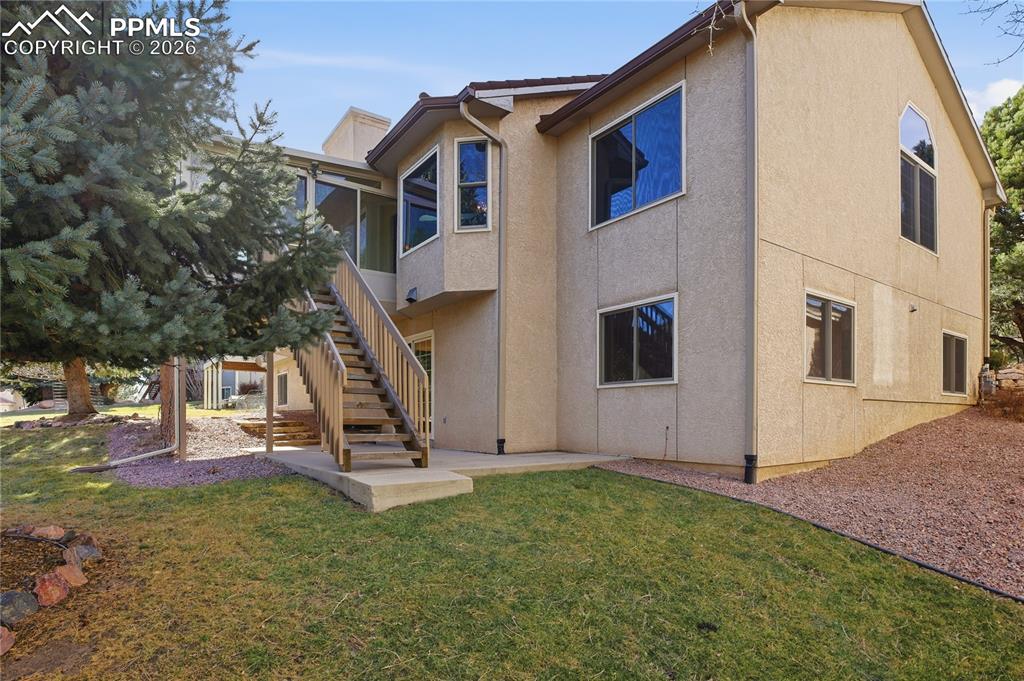Image 46 of 47: Back of house featuring stairs, a yard, and stucco siding