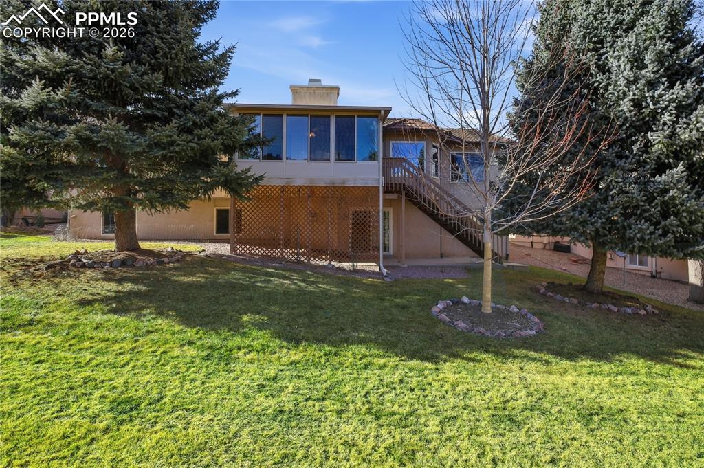 Image 47 of 47: Back of property with a chimney, a wooden deck, stairway, a lawn, and a pat