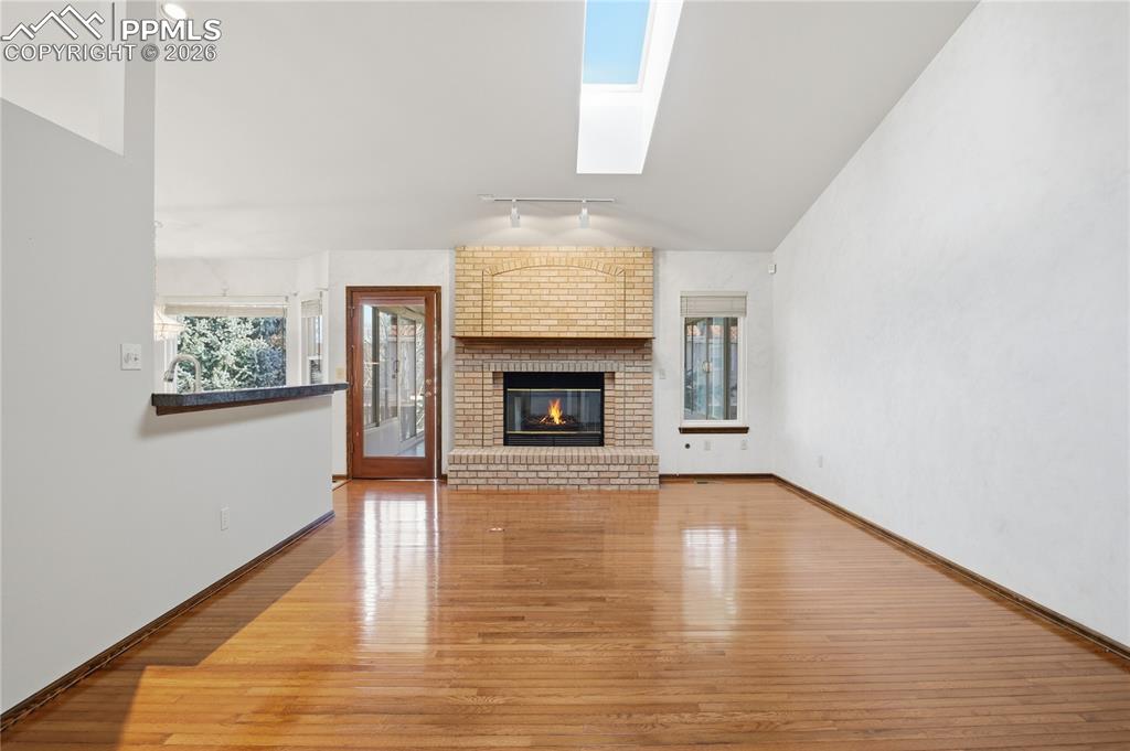 Image 6 of 47: Unfurnished living room featuring a skylight, a fireplace, light wood-type 