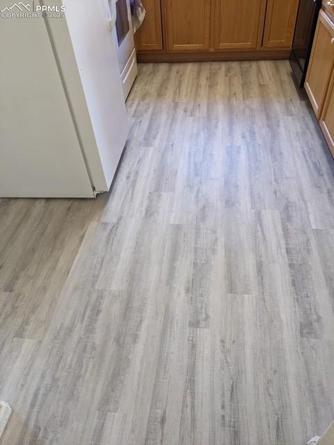 Image 12 of 29: Kitchen view of refrigerator, brown cabinets, light wood-style flooring,