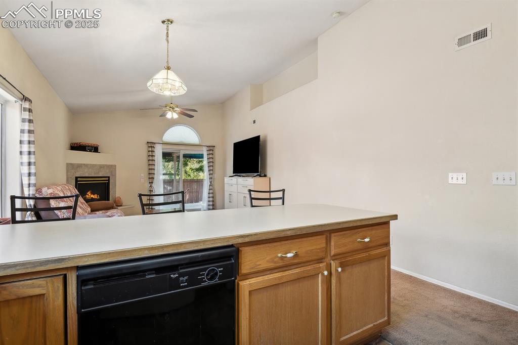 Image 13 of 29: Kitchen with light carpet, decorative light fixtures, lofted ceiling, and c