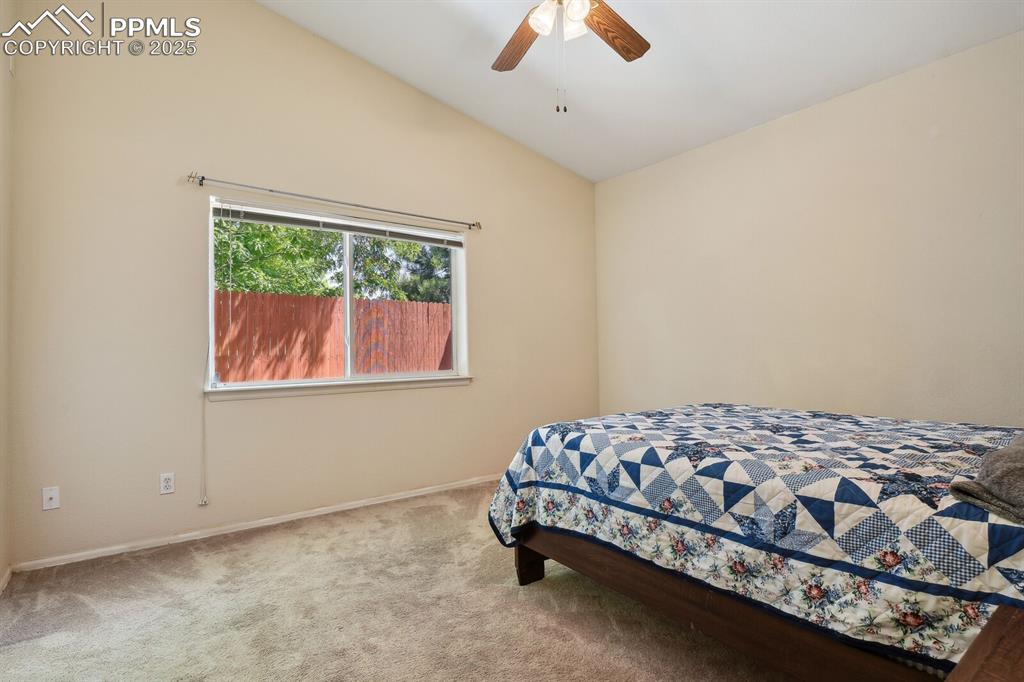 Image 19 of 29: Carpeted bedroom featuring lofted ceiling and ceiling fan
