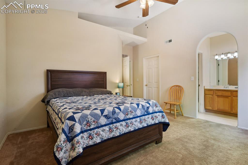Image 20 of 29: Bedroom with high vaulted ceiling, connected bathroom, carpet flooring, cei