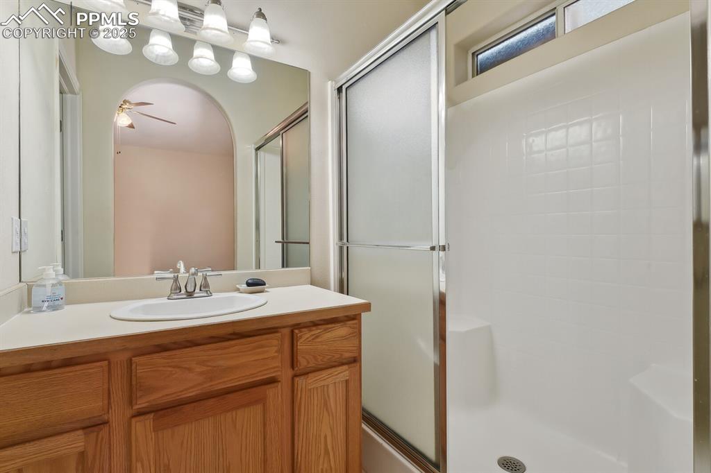 Image 21 of 29: Bathroom with a shower with door, ceiling fan, and vanity