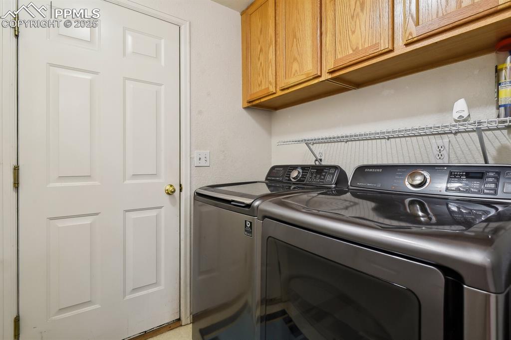 Image 25 of 29: Laundry room featuring separate washer and dryer and cabinets