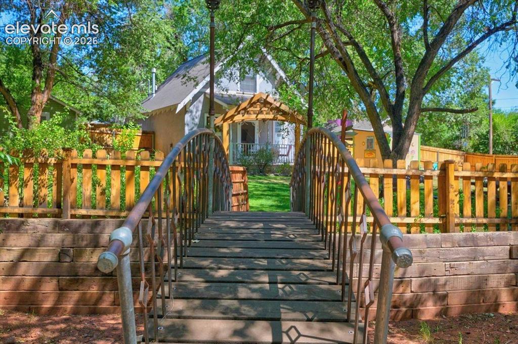 Image 47 of 50: 48. Garden Bridge – Decorative bridge leading into the beautifully landscap