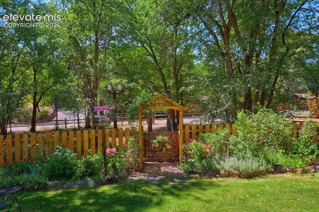Image 48 of 50: Garden Entrance – Welcoming garden gate surrounded by mature landscaping, c