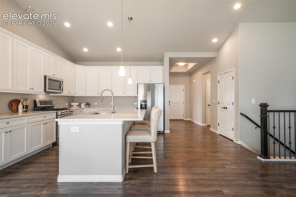 Image 4 of 49: Modern kitchen featuring white cabinetry, stainless steel appliances, a cen