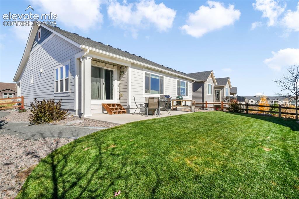 Image 47 of 49: Spacious backyard featuring a manicured lawn and a concrete patio