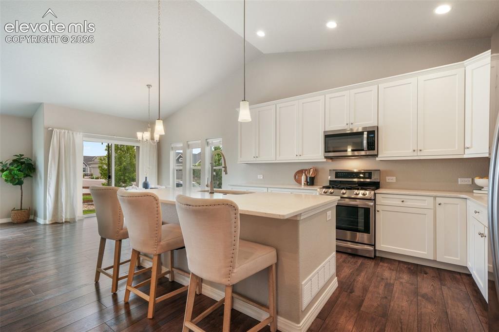 Image 7 of 49: Open-concept kitchen featuring white cabinetry, stainless steel appliances,