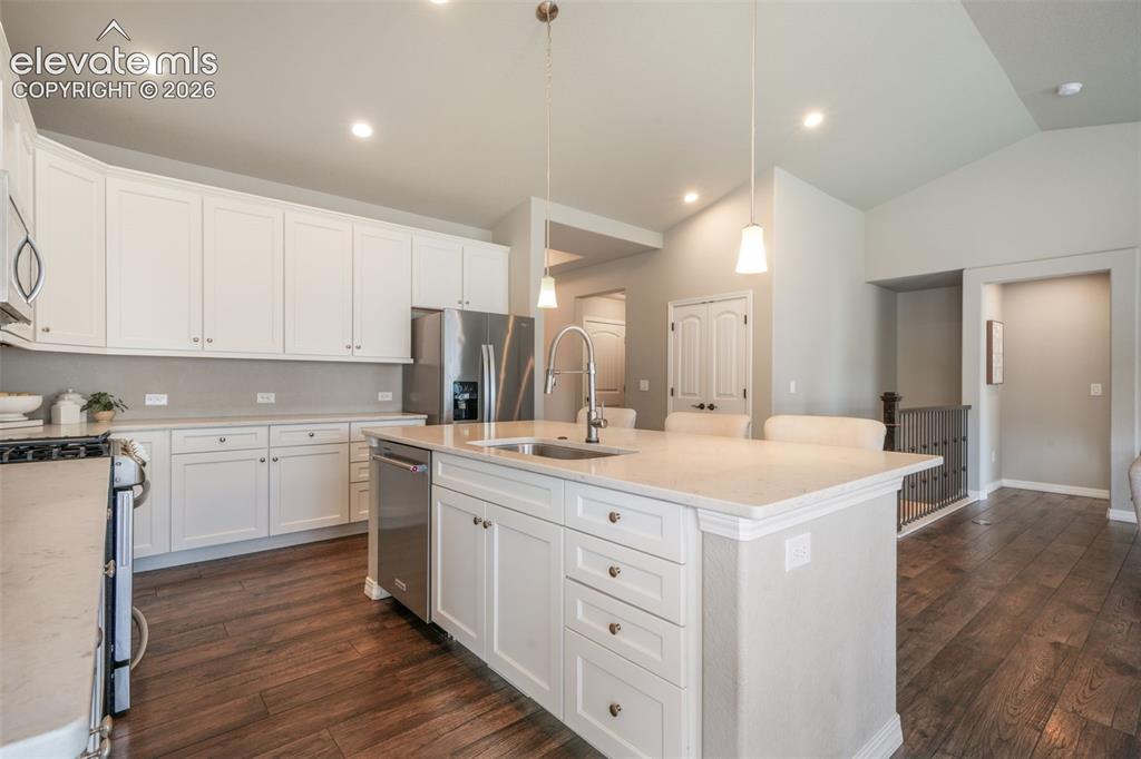Image 9 of 49: Kitchen featuring a substantial island with integrated sink, white cabinetr