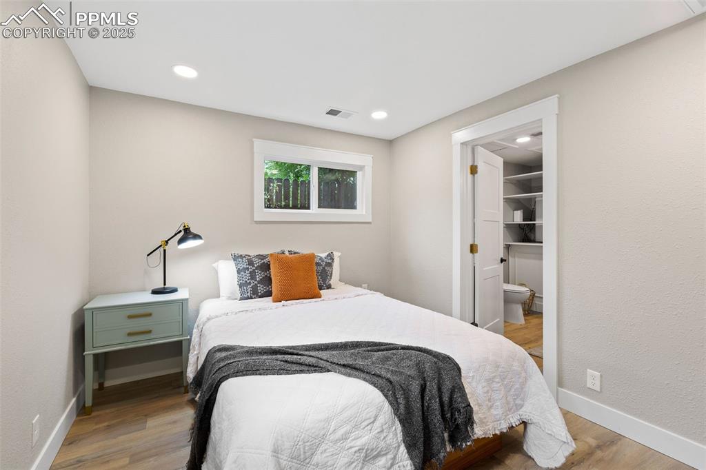 Image 13 of 15: Bedroom featuring light wood-style floors, a textured wall, ensuite bathroo
