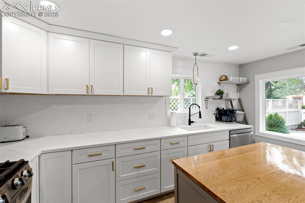 Image 8 of 15: Kitchen with open shelves, tasteful backsplash, recessed lighting, stainles