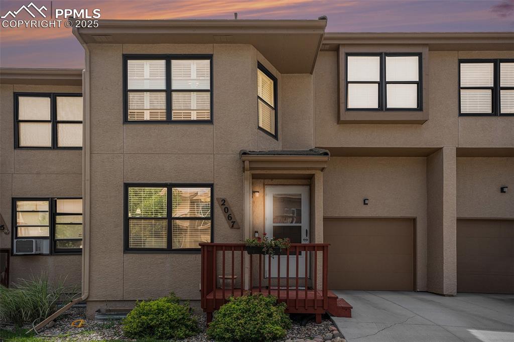 Caption: View of front of house with stucco siding, an attached garage, and newer concrete driveway