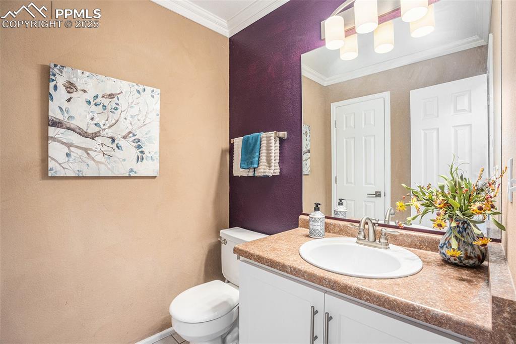 Image 6 of 23: Half Bathroom on main featuring vanity, crown molding, and upgraded lightin