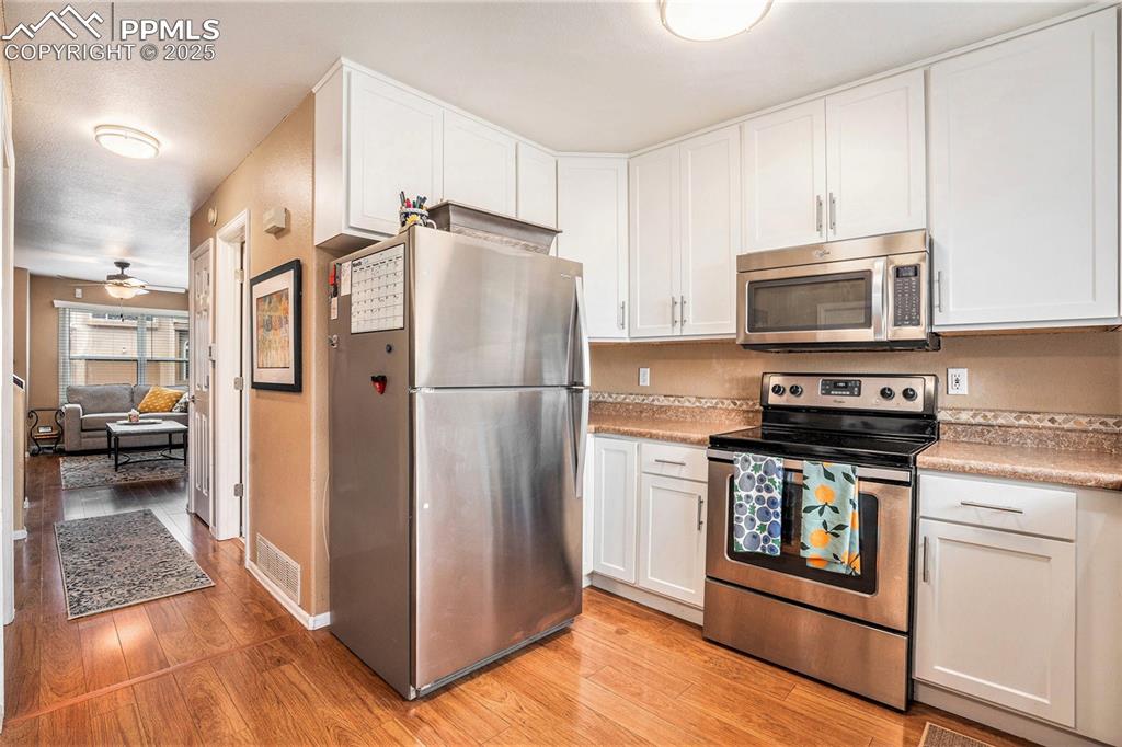 Image 7 of 23: Kitchen featuring stainless steel appliances, recently refaced white cabine