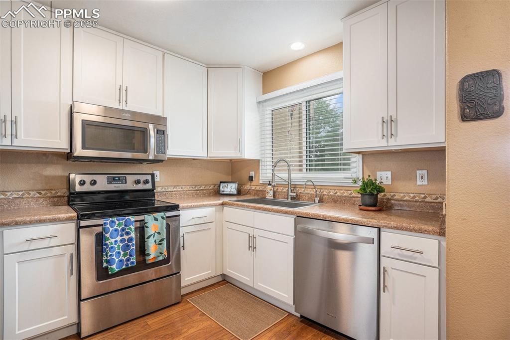 Image 8 of 23: Kitchen with stainless steel appliances, light flooring, and white cabinets