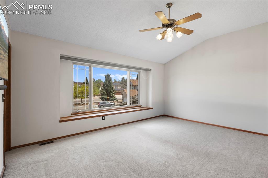 Image 16 of 46: This room features a vaulted ceiling, a ceiling fan with integrated lightin