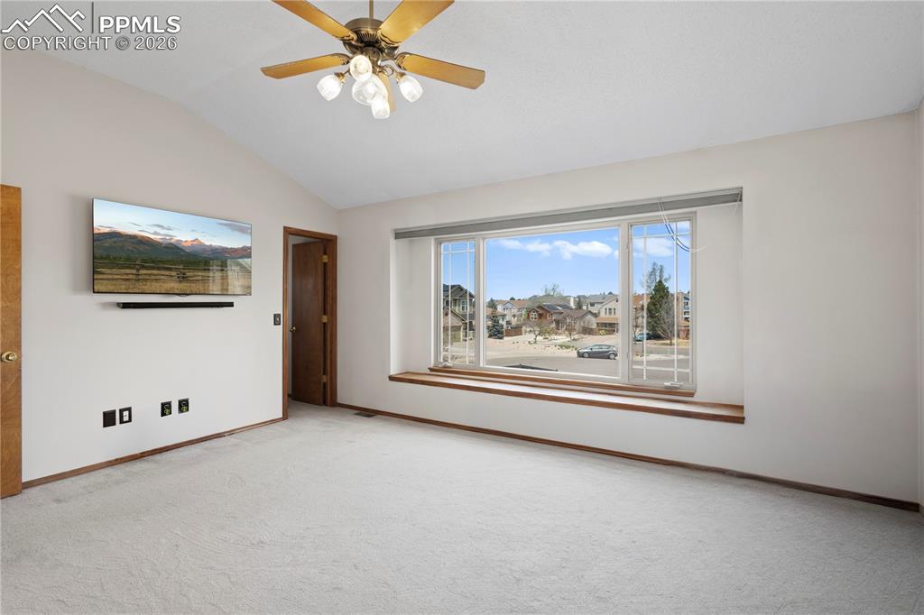Image 17 of 46: The property features a spacious room with vaulted ceilings and a ceiling f