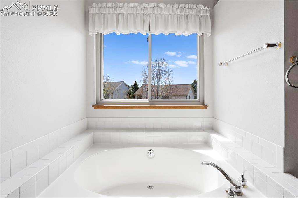 Image 21 of 46: The bathroom features a built-in bathtub with white tiled surround, a chrom
