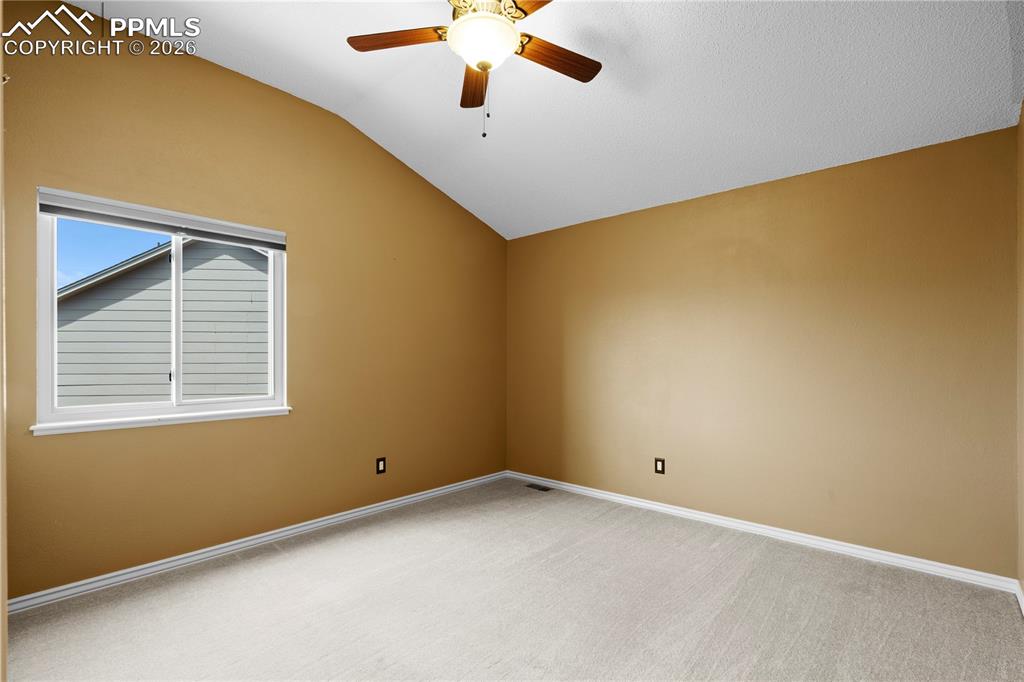 Image 27 of 46: This room features a vaulted ceiling, a ceiling fan with integrated lightin