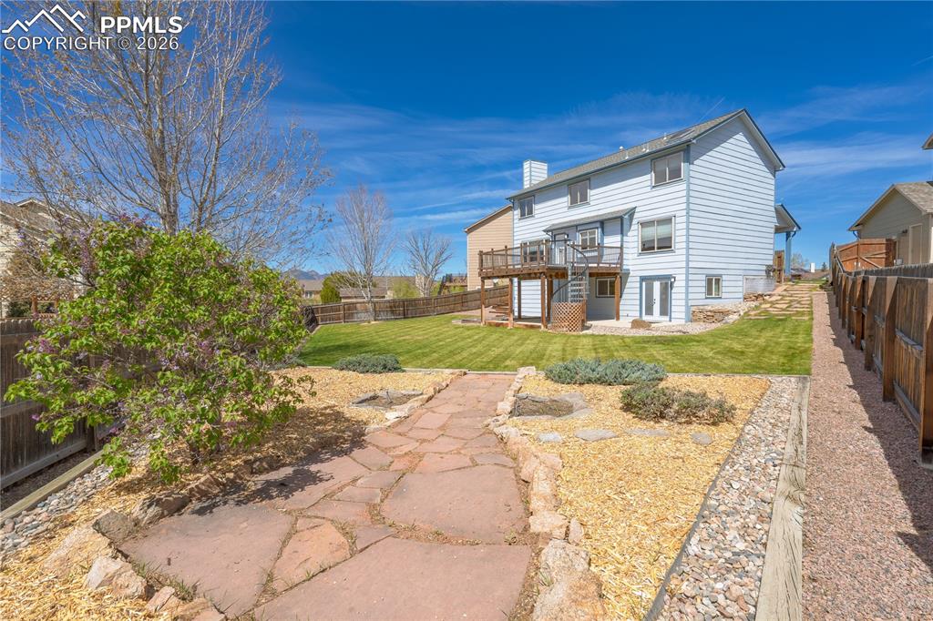 Image 38 of 46: The property features an extensive yard with a well-maintained lawn, a ston