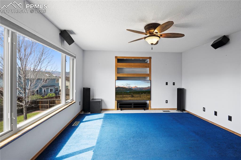 Image 8 of 46: Living room featuring a large window, a ceiling fan, and  carpeting