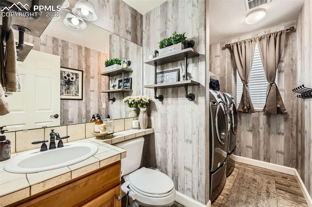 Image 11 of 30: Bathroom with washing machine and dryer, wood-style floors, vanity, and woo