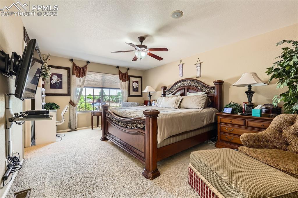 Image 15 of 30: Bedroom with light carpet, a textured ceiling, and ceiling fan