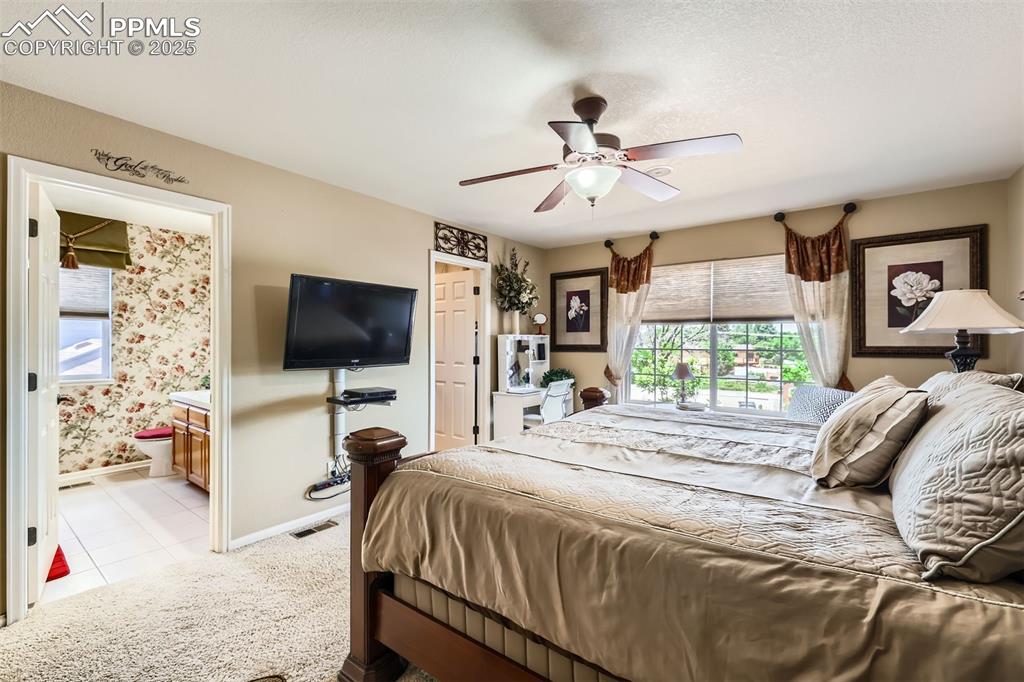 Image 16 of 30: Master bedroom featuring light colored carpet, ensuite bath, light tile pat