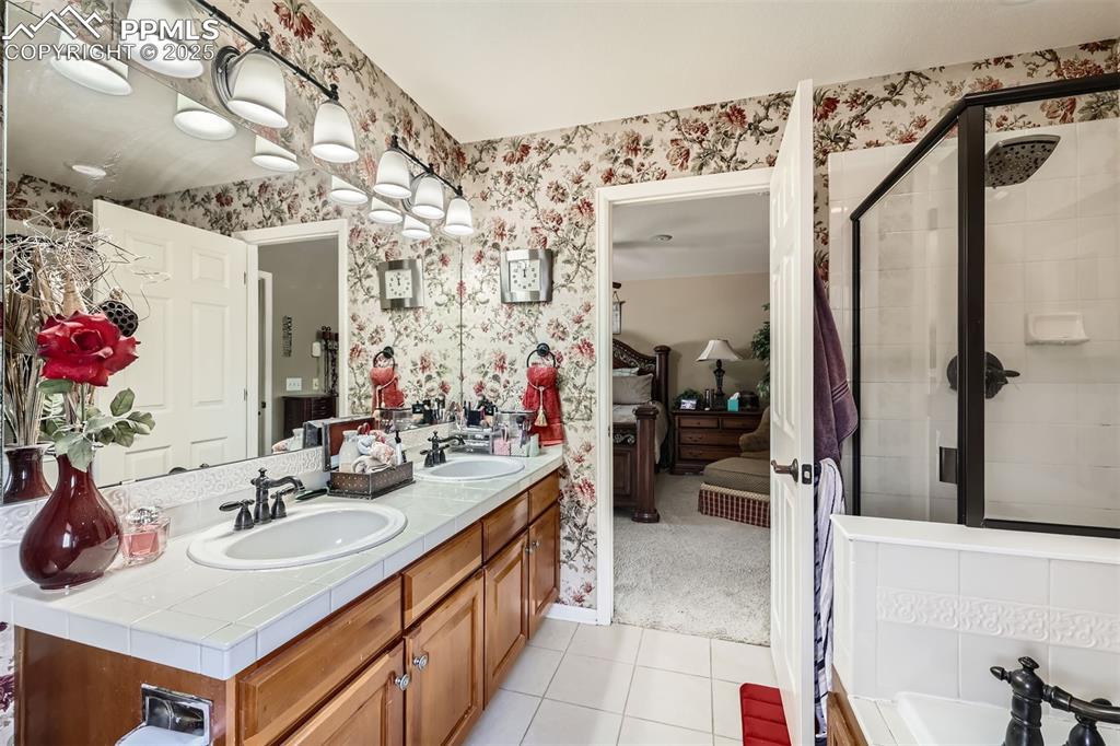 Image 17 of 30: Ensuite bathroom with wallpapered walls, tile patterned flooring, double va