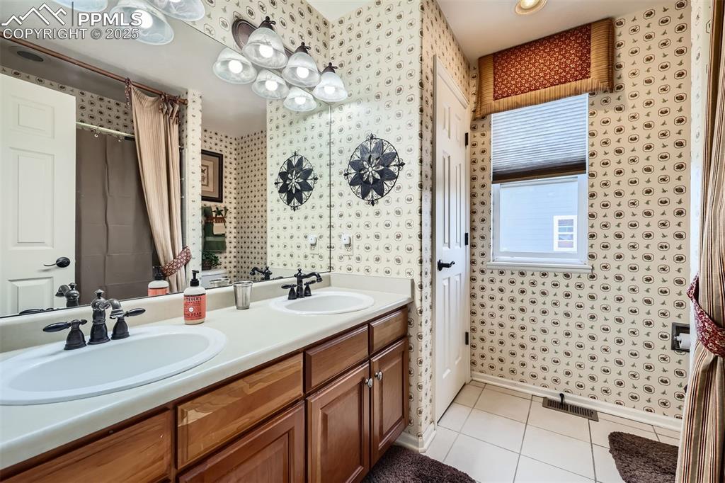 Image 19 of 30: Full bathroom featuring wallpapered walls, tile patterned floors, double va