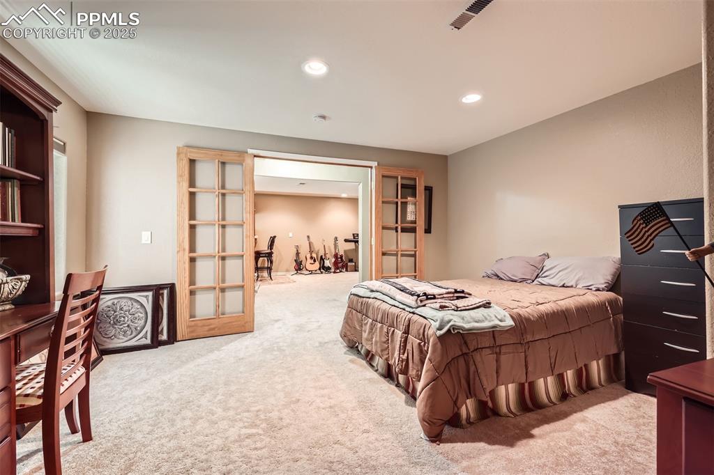 Image 26 of 30: Bedroom with French doors, carpet floors, and recessed lighting
