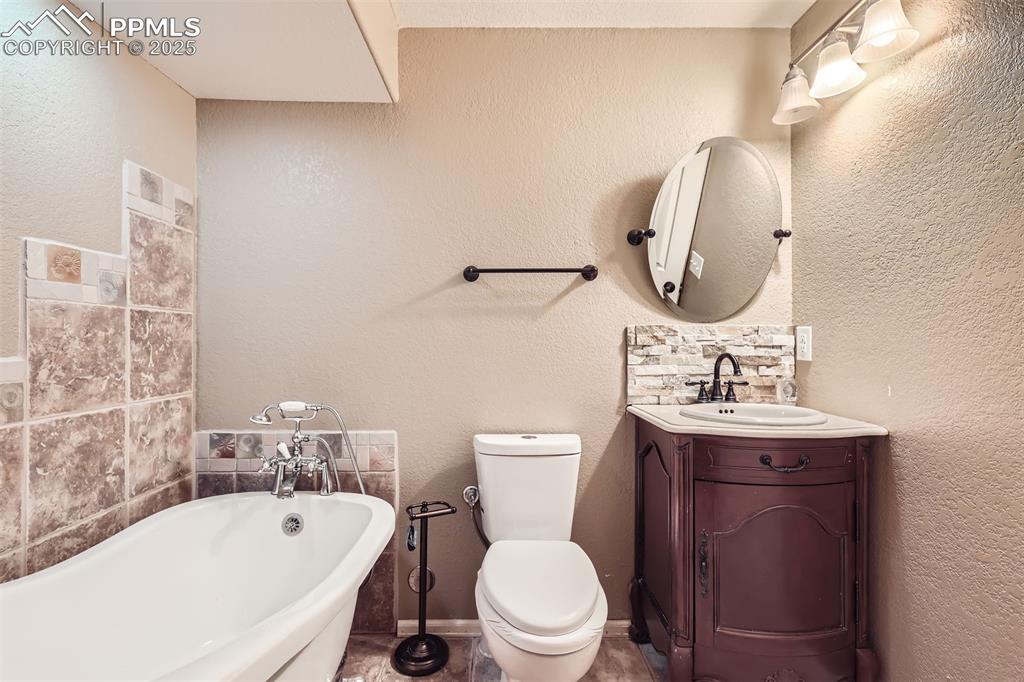 Image 28 of 30: Full bath featuring a freestanding slipper tub and vanity