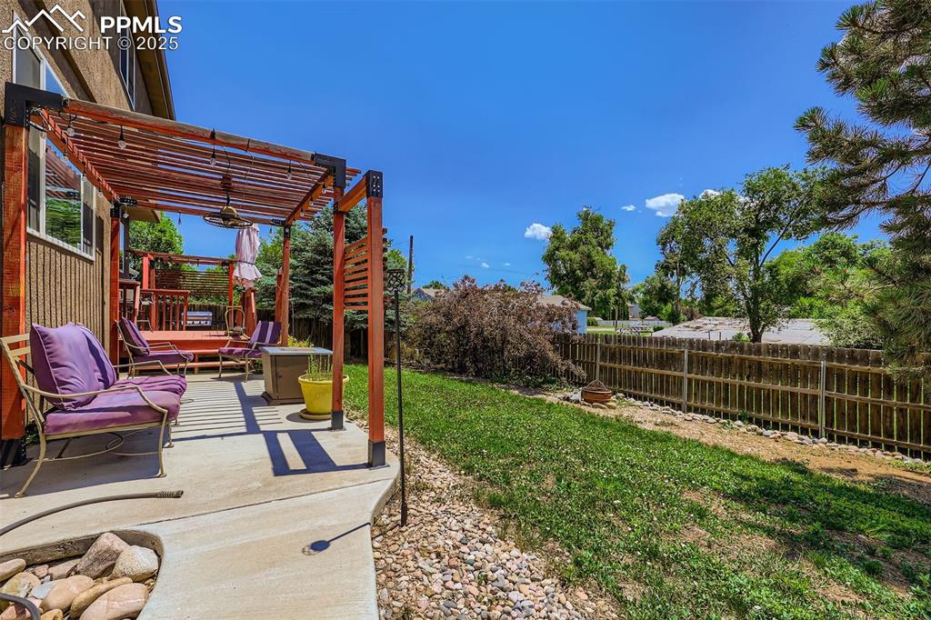 Image 29 of 30: Fenced backyard with a pergola and a patio