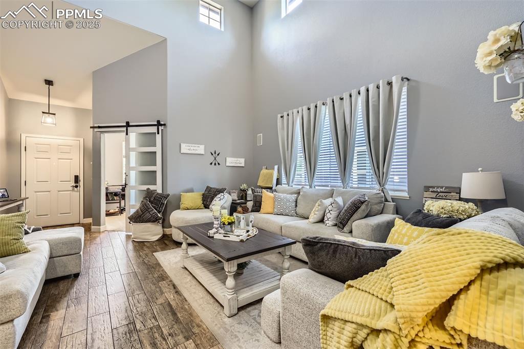 Image 4 of 30: Living room featuring a towering ceiling, a barn door, and dark wood-style 