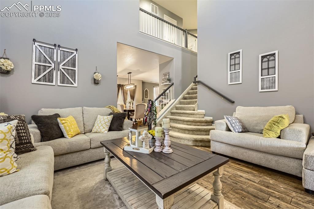 Image 5 of 30: Living room featuring stairway, a high ceiling, and wood-style floors